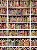 A series of bookshelves filled with books that have vividly patterned and colorful covers. The books are arranged neatly, creating a visually striking display of geometric and abstract designs. Each book seems to have a unique combination of colors and patterns, ranging from stripes and dots to floral and geometric motifs.