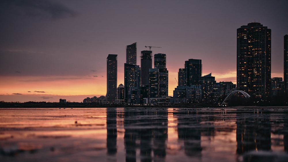 city skyline across body of water during night time