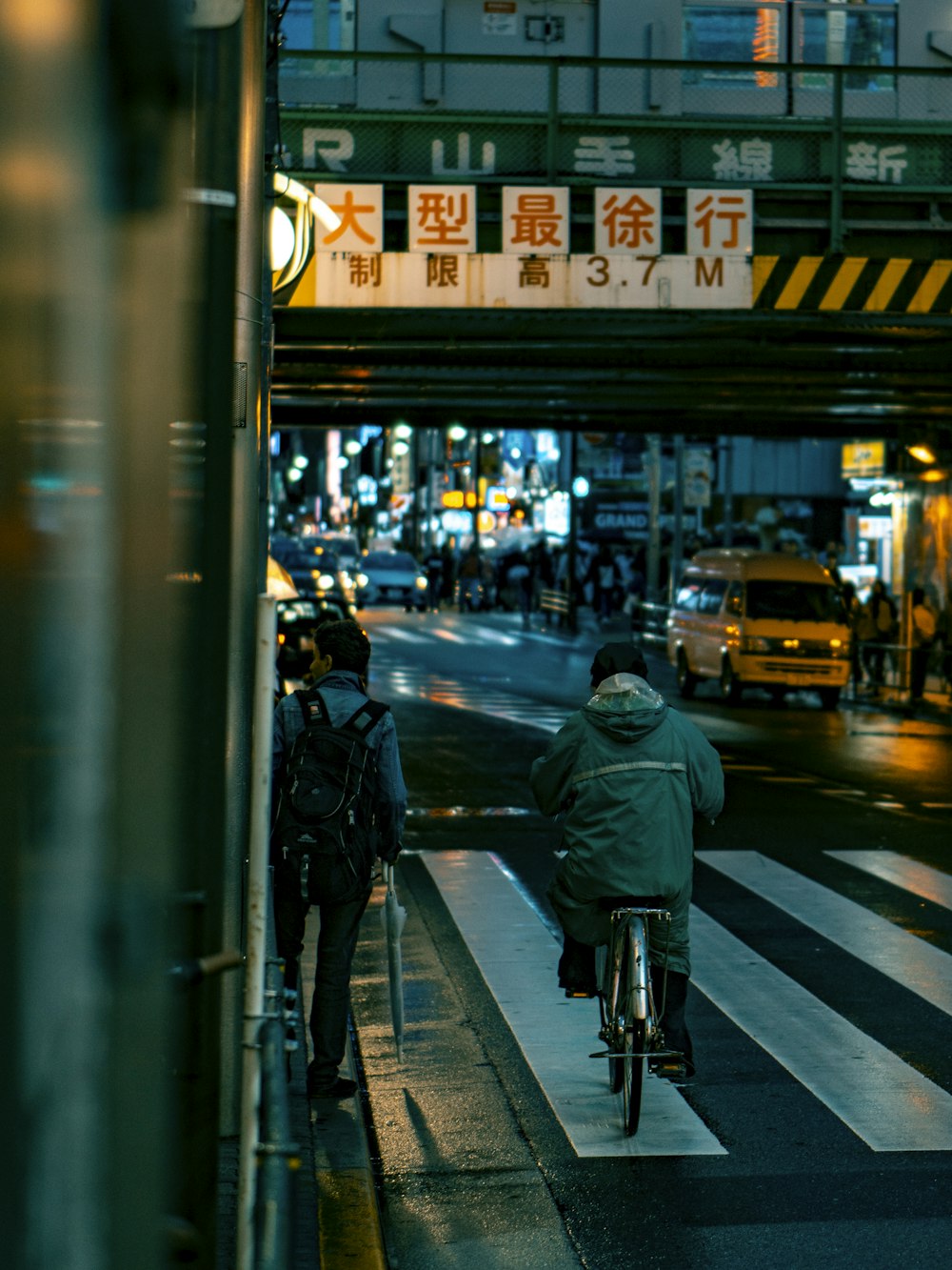 man in black jacket and black pants walking on pedestrian lane during night time