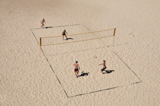 Volleyball players diving to save the ball on a sandy beach court