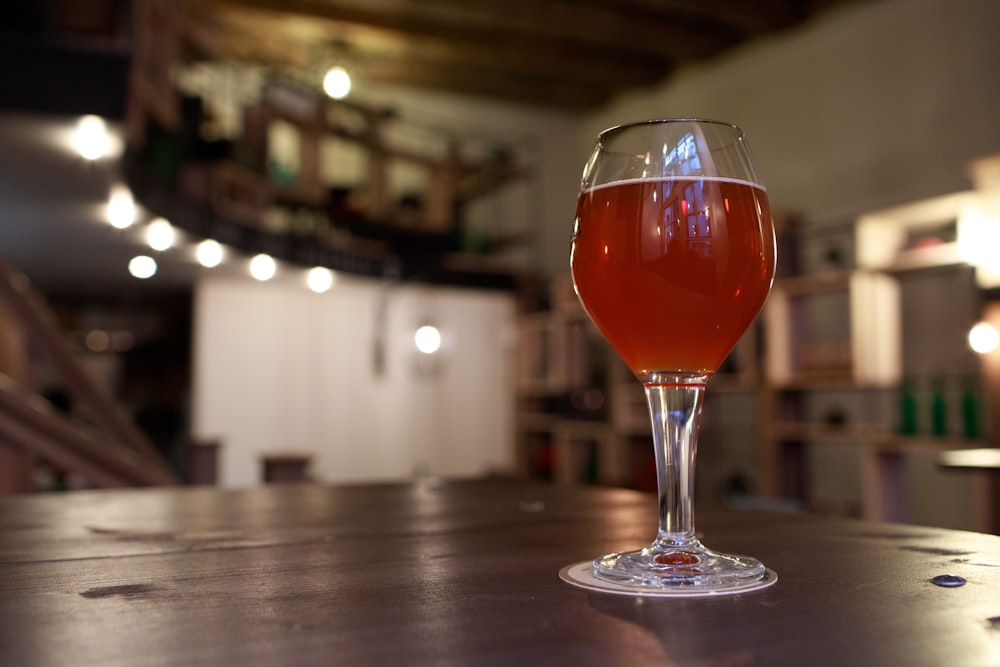 clear wine glass with red liquid on brown wooden table