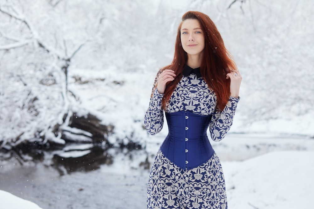 donna in abito floreale blu e bianco in piedi su terreno coperto di neve durante il giorno