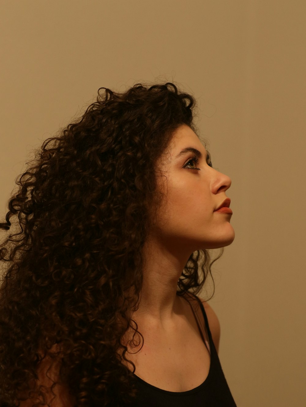 uma mulher com longos cabelos encaracolados em pé na frente de uma parede