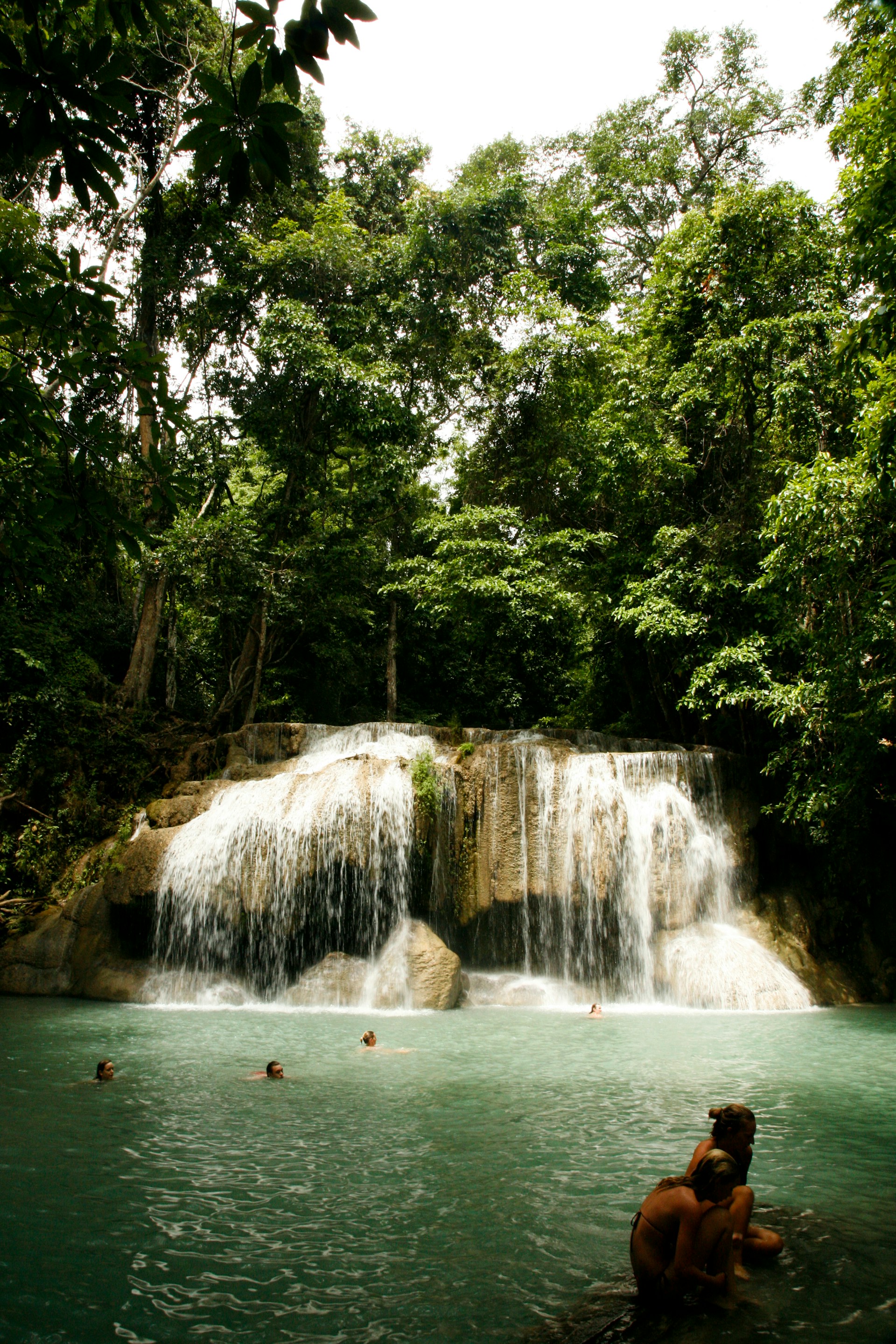 Guests enjoying the peaceful wooden deck of a cabin overlooking the serene natural pool formed by the waterfall.