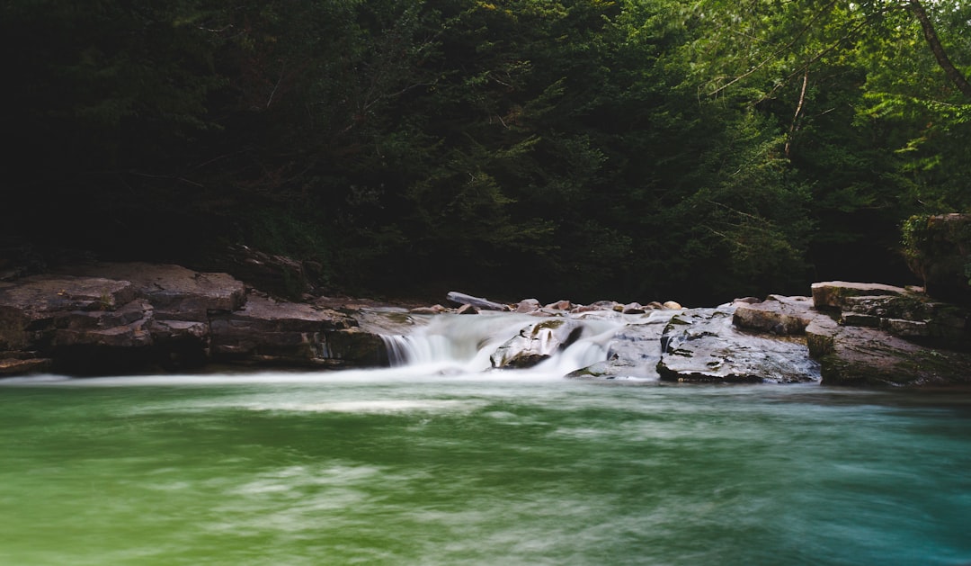 green body of water near brown rock formation during daytime