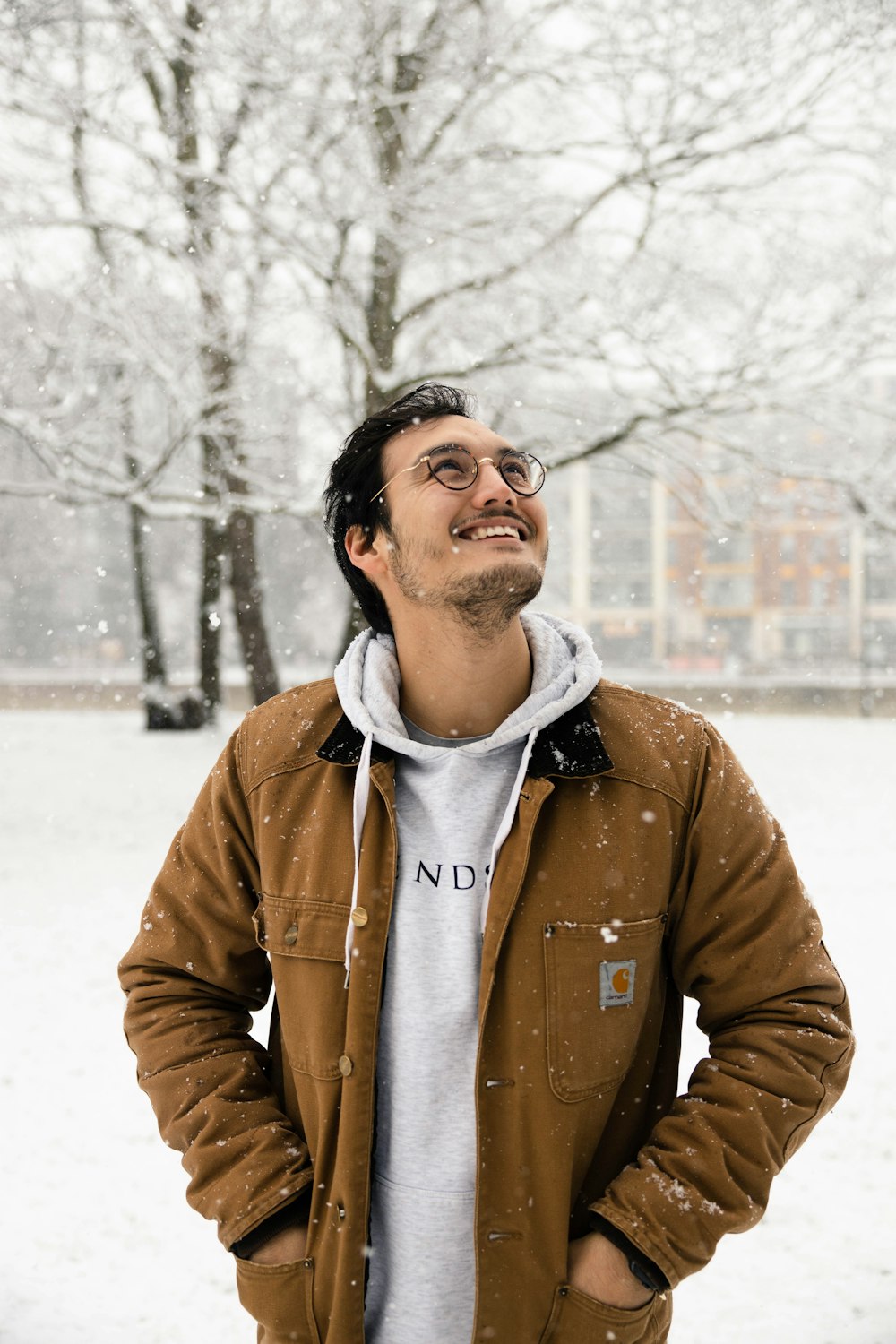 man in brown zip up jacket standing on snow covered ground during daytime