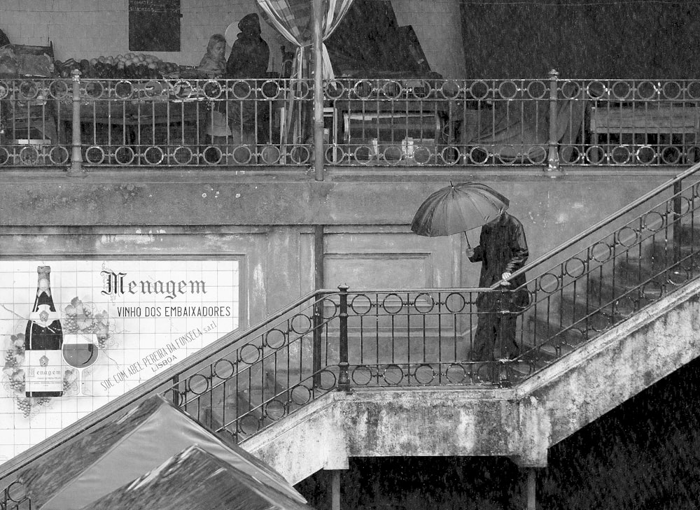 grayscale photo of woman in black jacket holding umbrella