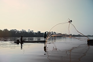 A peaceful early morning scene of a beginner fisherman casting a line into a misty riverbank.