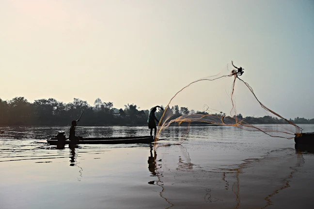 Angler casting a line from a drift boat on the calm San Juan River at sunrise