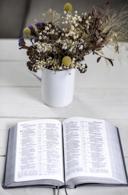 A delicate bouquet of pastel wildflowers resting on an open Bible with handwritten notes.