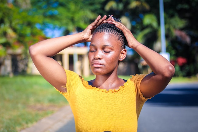 woman in yellow crew neck shirt holding her hair