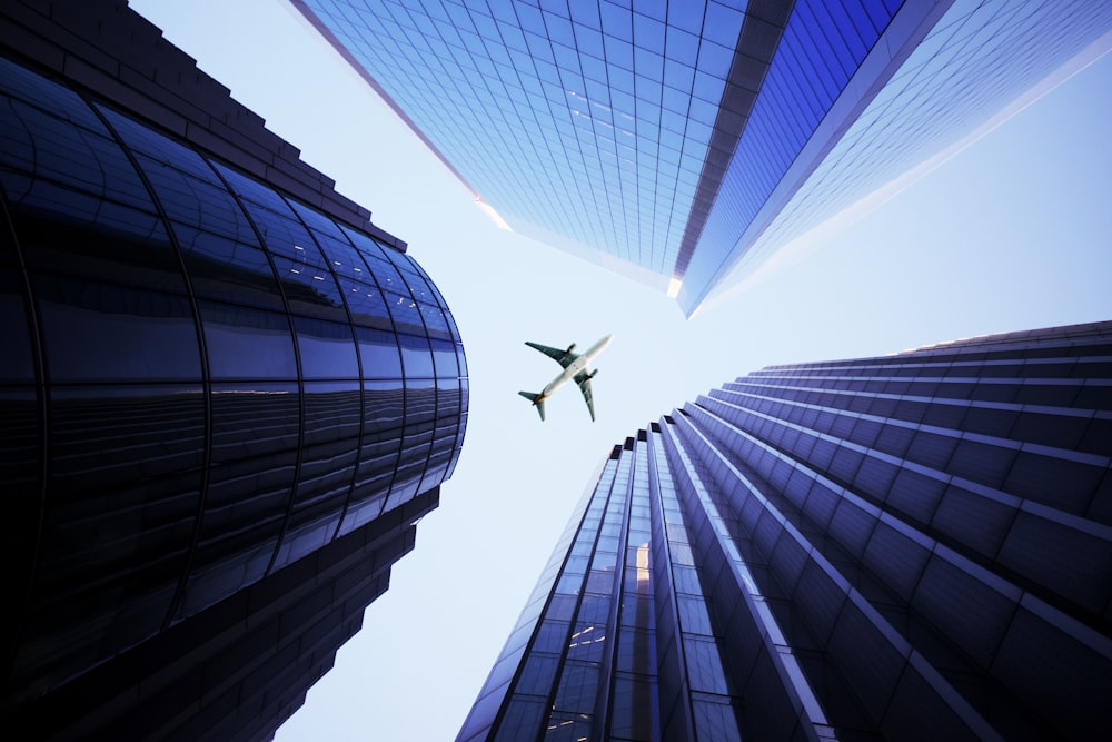 white airplane flying over the high rise building during daytime