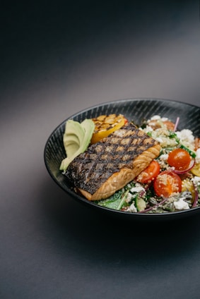 grilled meat with green vegetable on black ceramic plate
