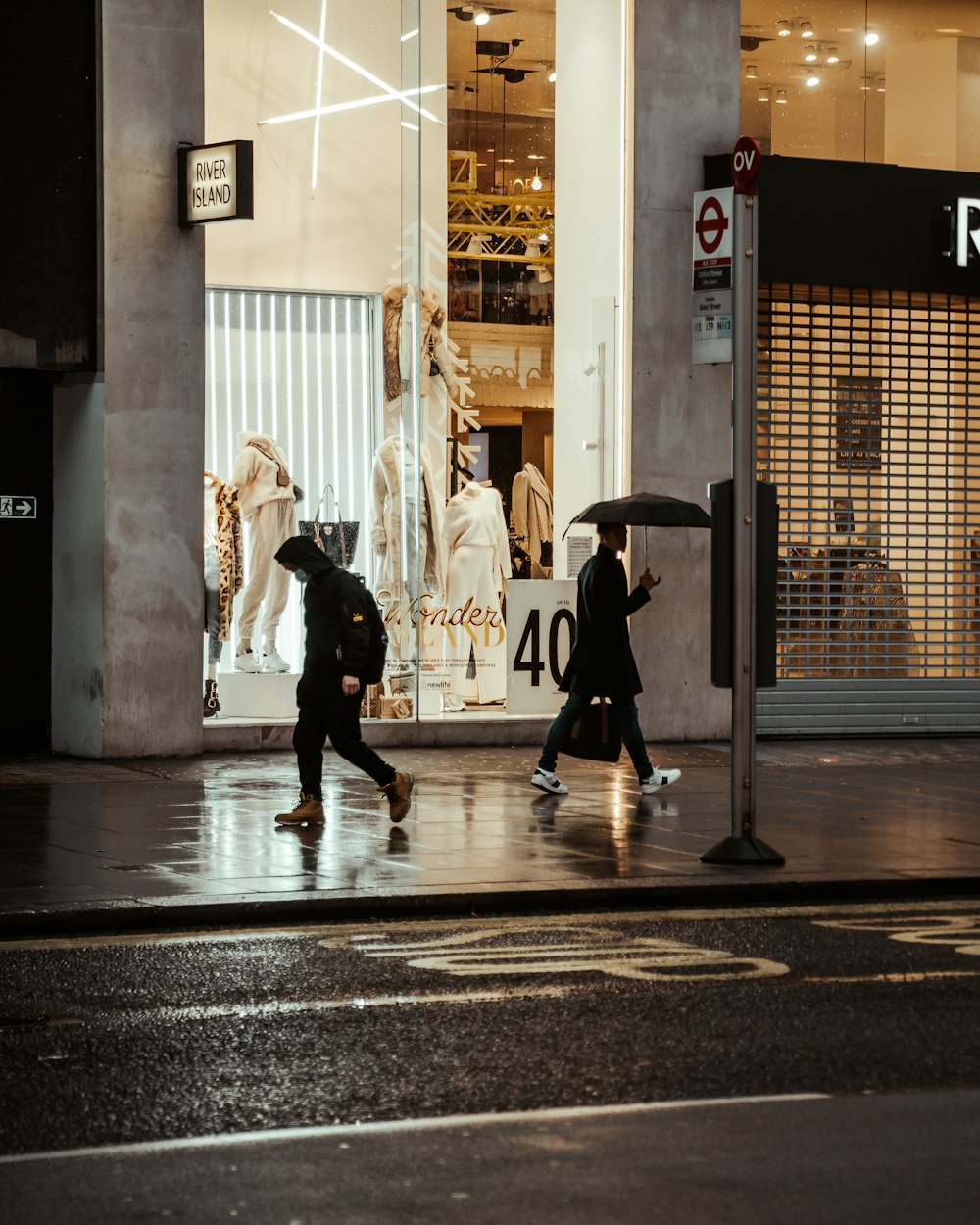 man in black jacket walking on sidewalk during night time