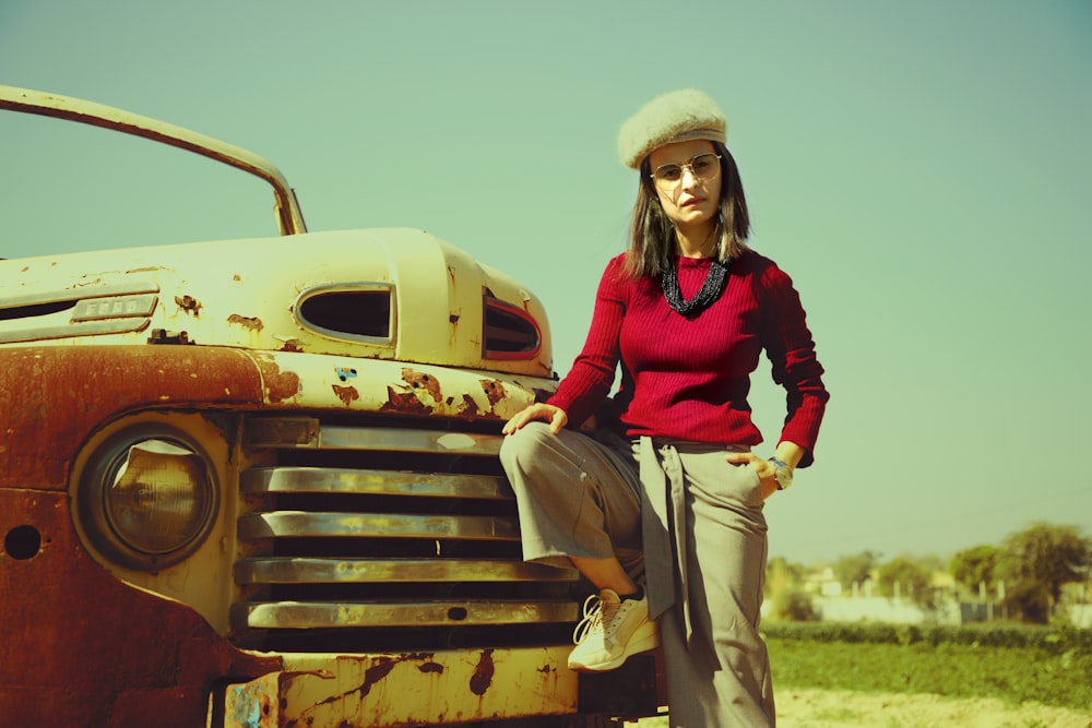 woman in red sweater and brown pants standing beside yellow car during daytime