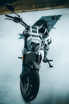 A sleek, modern motorcycle with a robust build is captured from the front angle. The bike features a prominent headlight, wide tires, and sturdy handlebars. The background is minimalistic, highlighting the motorcycle's design.