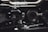 Intricate mechanical components featuring gears, chains, and metal parts, likely part of an engine or machinery. The image highlights metallic textures and detailed craftsmanship.