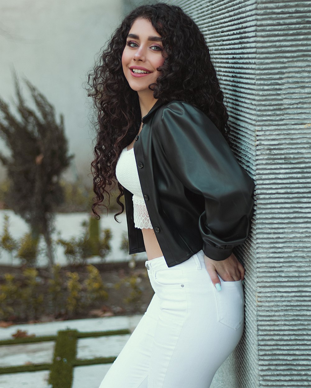 woman in black blazer and white dress pants leaning on wall