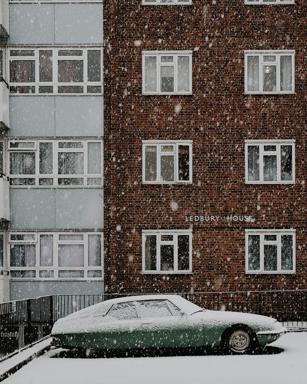 white car parked beside brown brick building