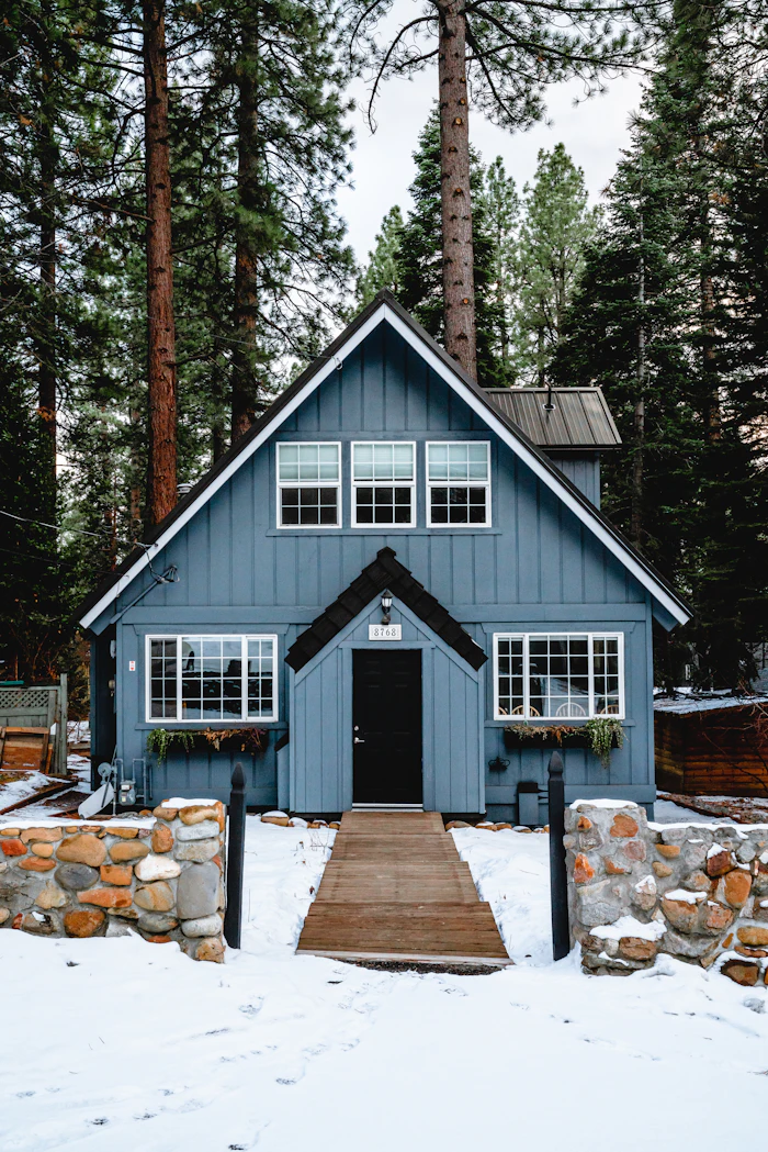 A blue gabled house among tall pines