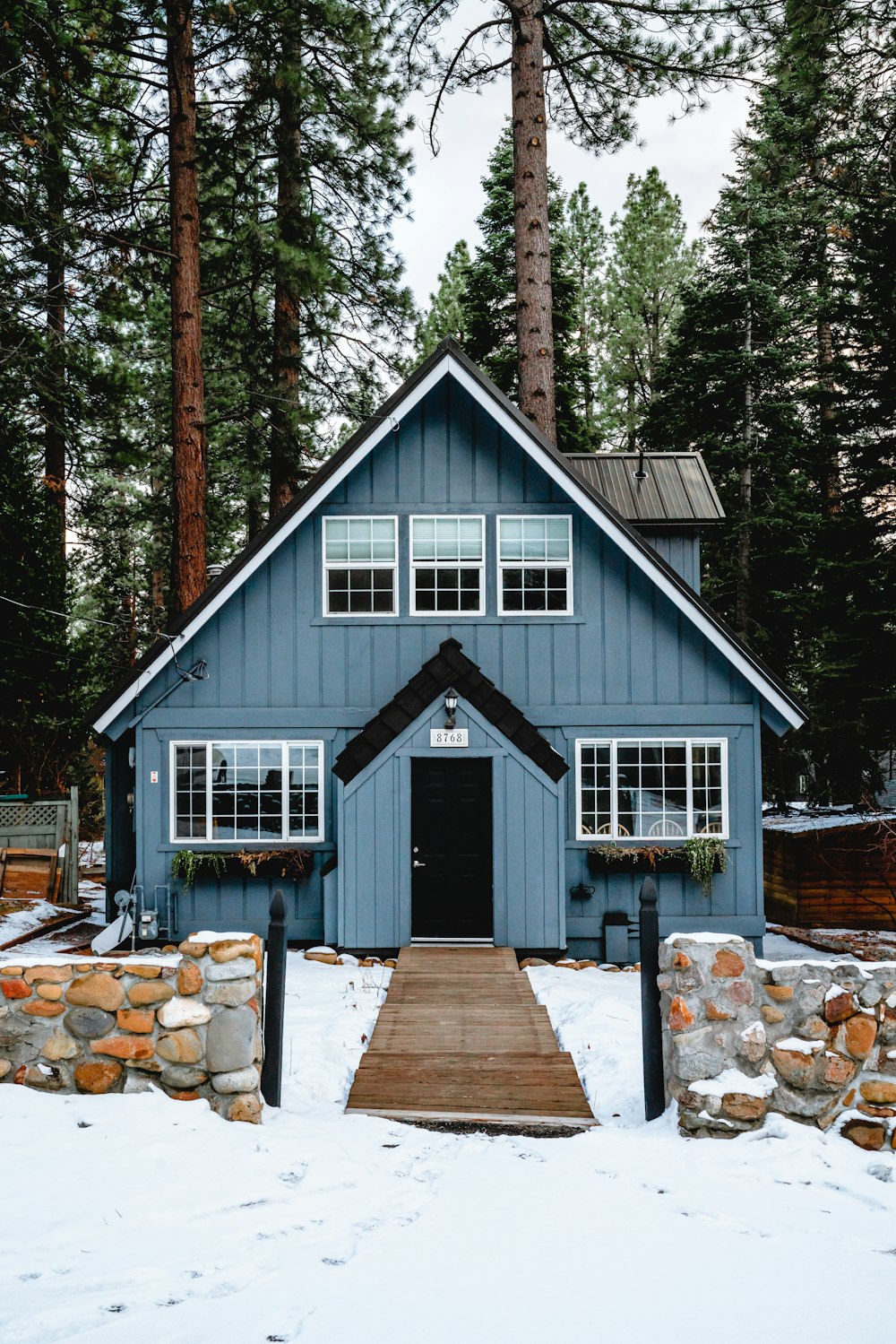 Maison en bois blanc et brun près des arbres verts pendant la journée