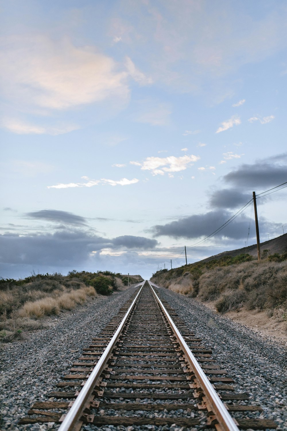 rail de train en métal gris sous les nuages blancs pendant la journée