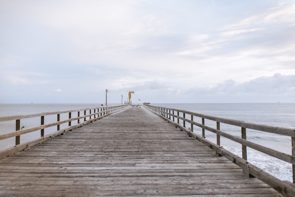 brown wooden dock on sea under white clouds during daytime