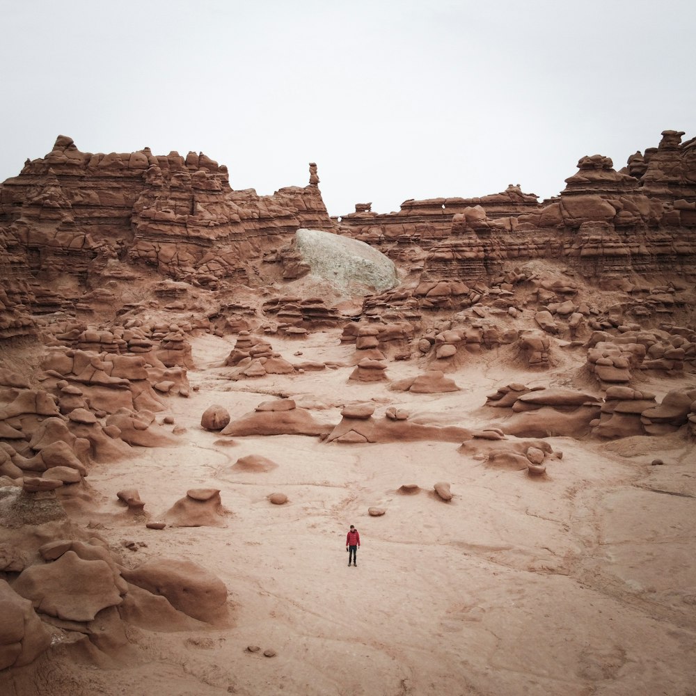 Persona con chaqueta roja caminando sobre arena marrón durante el día