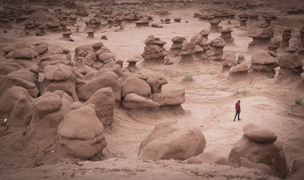 woman in black jacket walking on brown sand during daytime