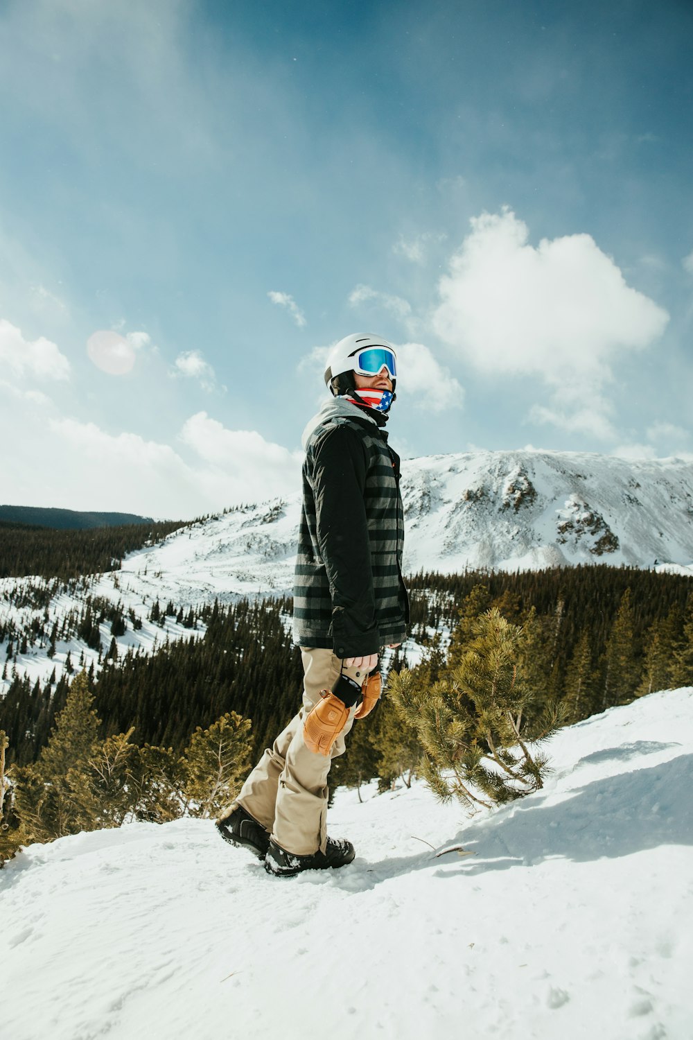 person in black jacket and brown pants standing on snow covered ground during daytime