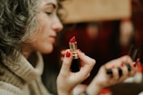 woman in gray sweater holding lipstick