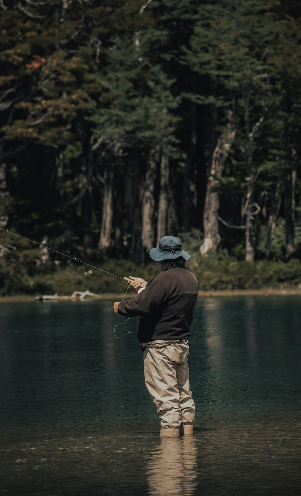 man in black jacket fishing on lake during daytime