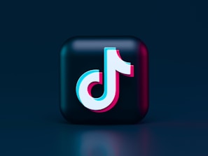 A three-dimensional cube features a stylized logo in the center, composed of a musical note shape. The logo is rendered in bright colors, contrasting against a dark background, with a glossy, modern aesthetic.