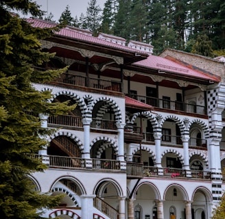 white and red concrete building surrounded by green trees during daytime