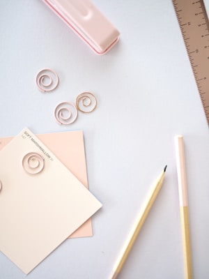 Soft pastel-colored stationery items spread out on a clean white desk.