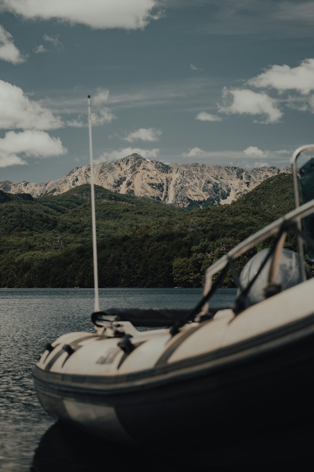 white and black boat on water near mountain during daytime