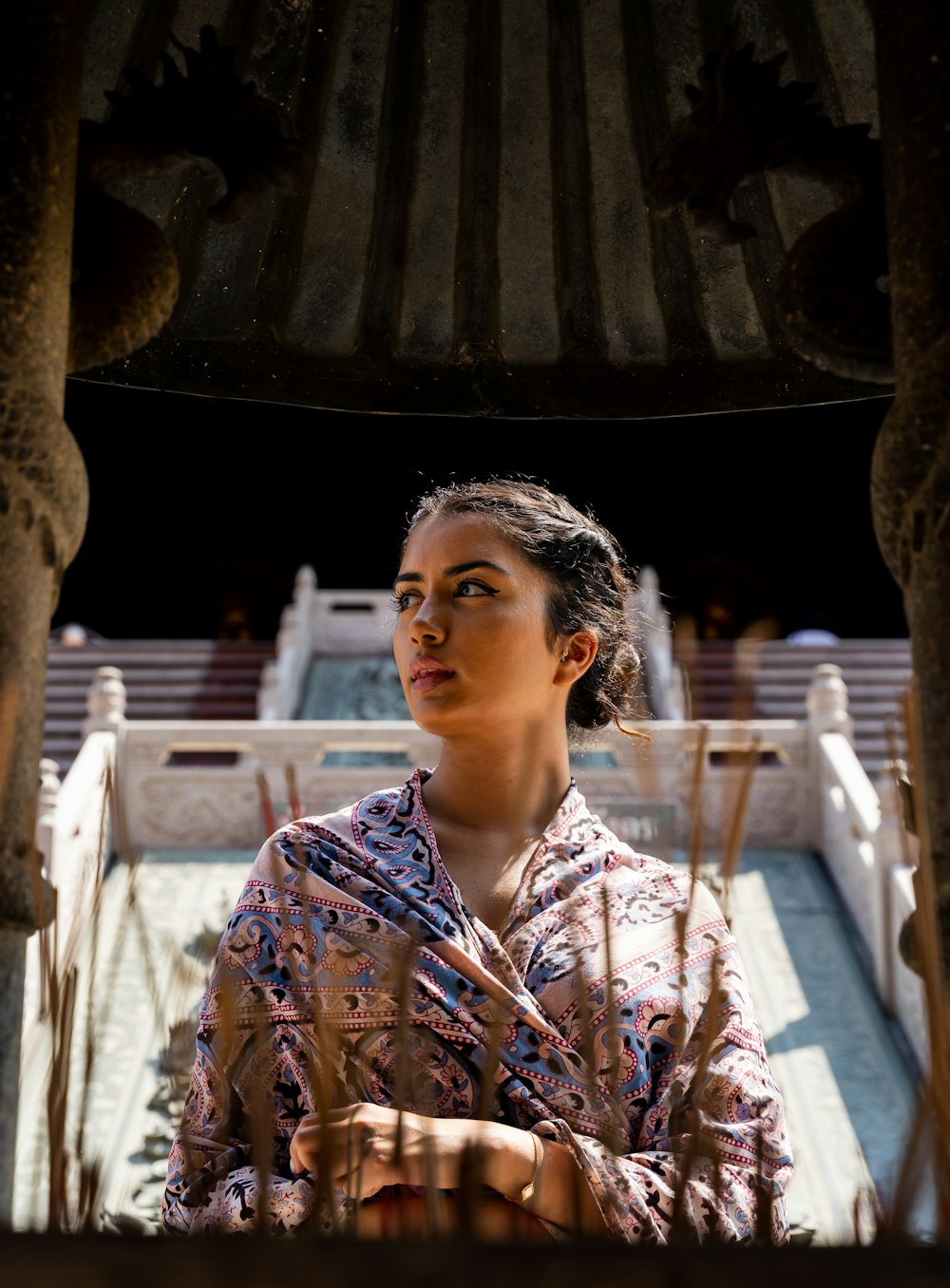 woman in blue and white floral button up shirt standing near brown wooden post during daytime