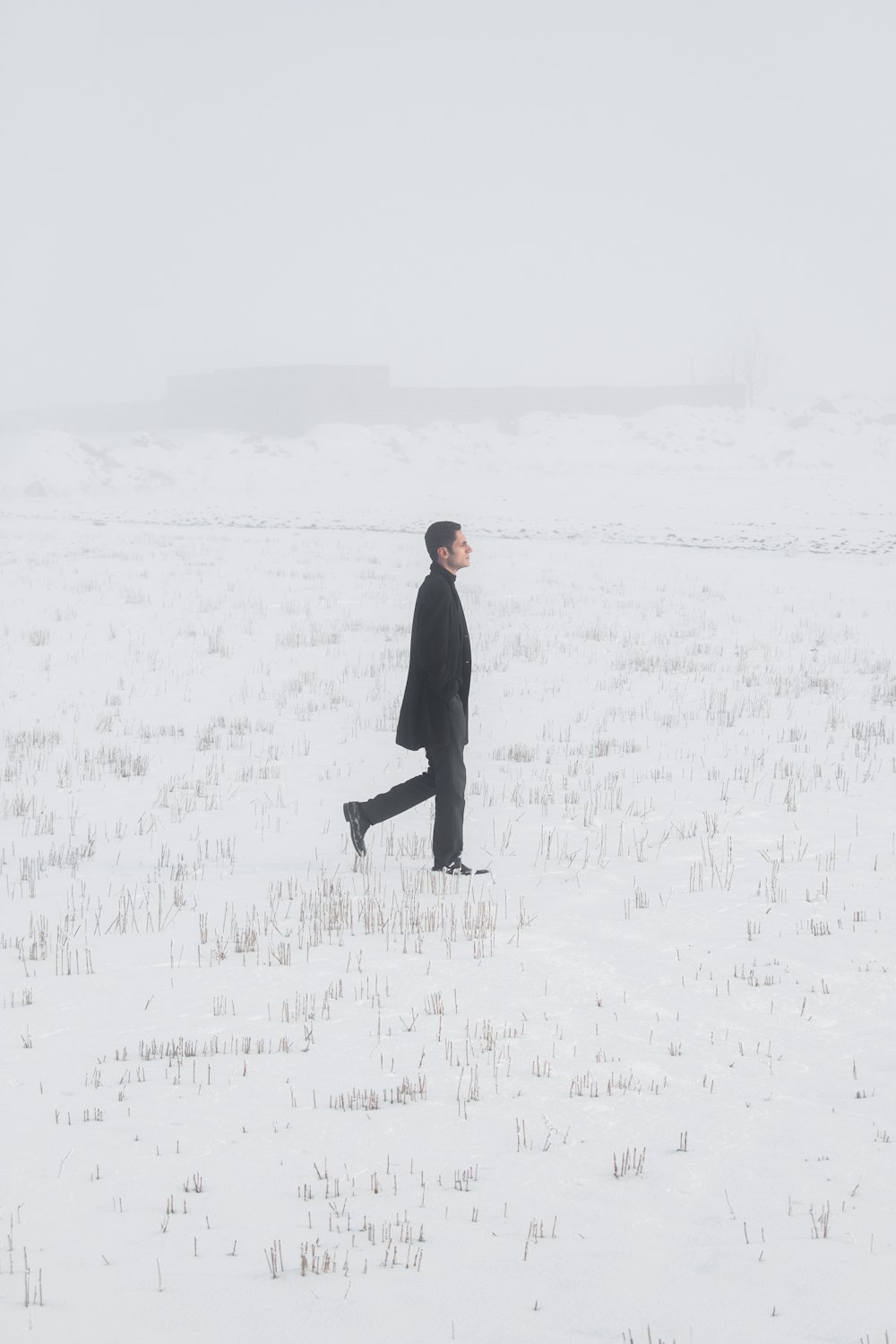 man in black coat walking on snow covered field during daytime