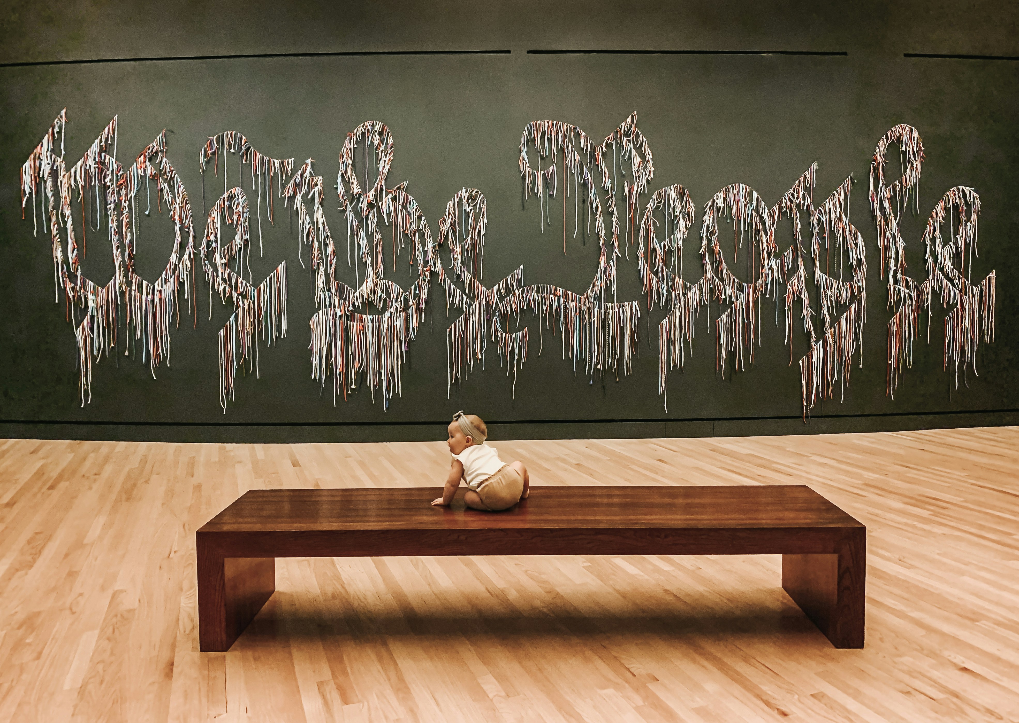 a teddy bear sitting on a bench in front of a painting