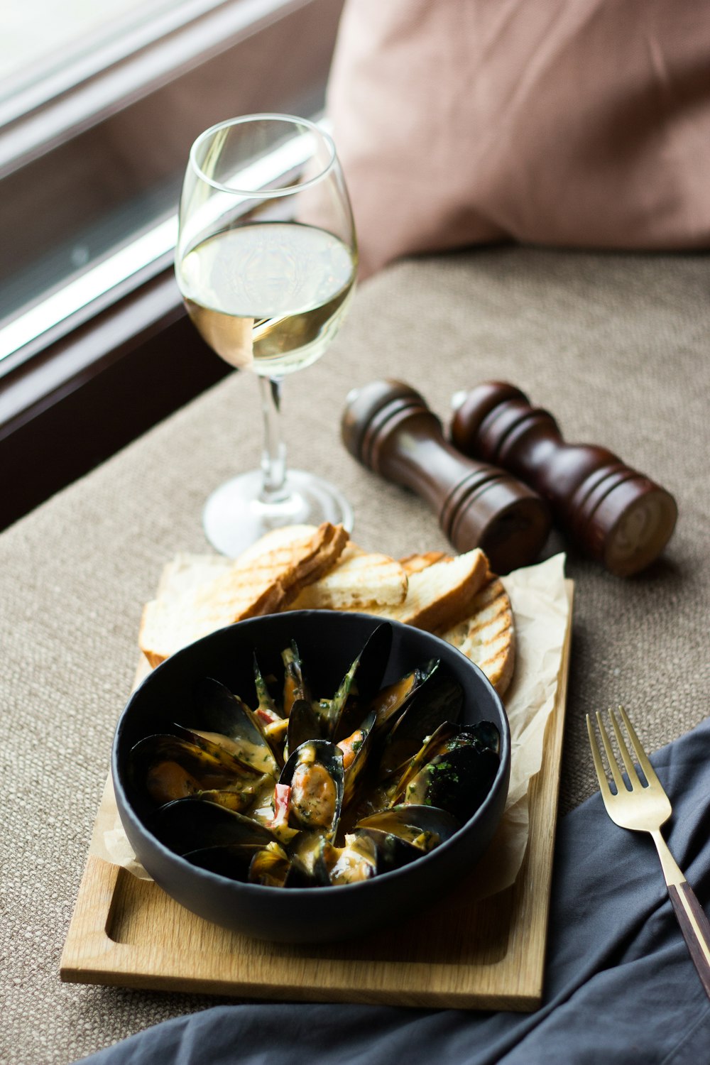 person holding fork and knife slicing food on black ceramic bowl