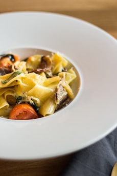 A vibrant, colorful plate of homemade pasta with fresh herbs and cherry tomatoes.