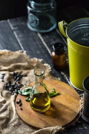 clear glass bottle beside green ceramic mug