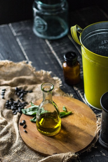 clear glass bottle beside green ceramic mug