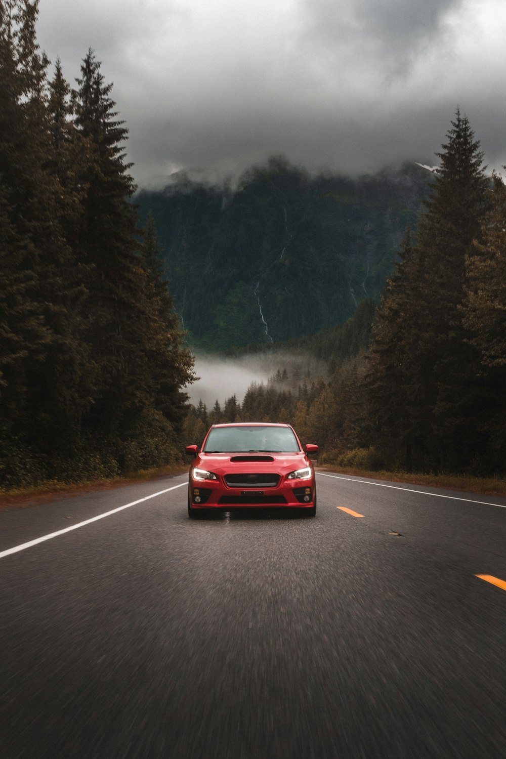 Coche rojo en la carretera cerca de los árboles durante el día