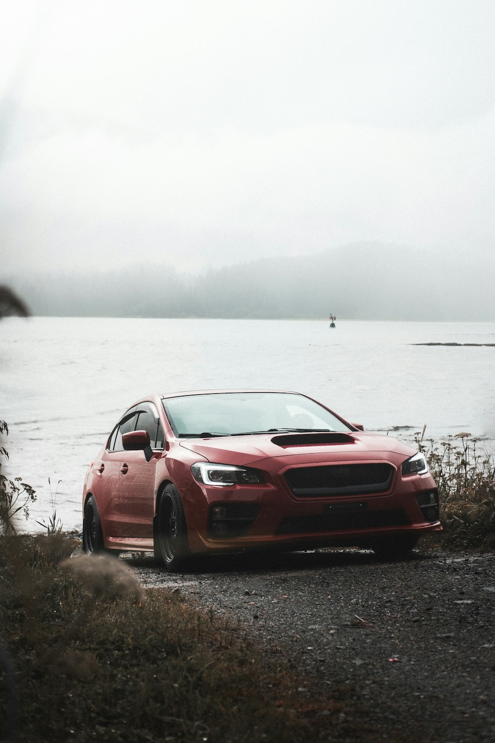 red bmw m 3 coupe parked near body of water during daytime