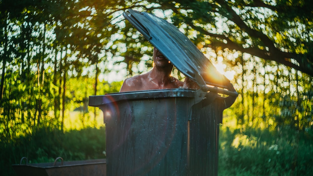 woman in blue umbrella in black trash bin