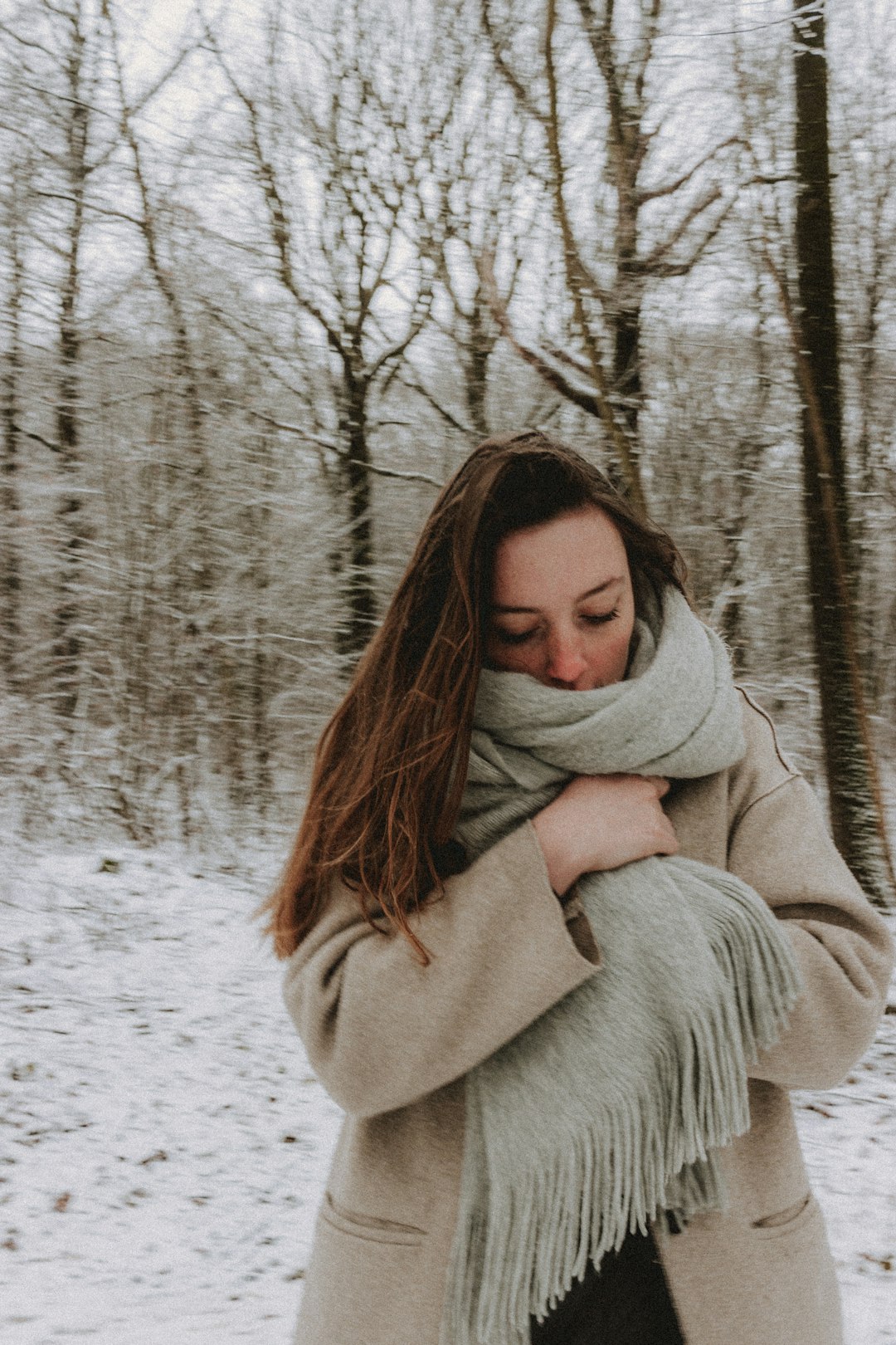 woman in gray coat standing on snow covered ground during daytime