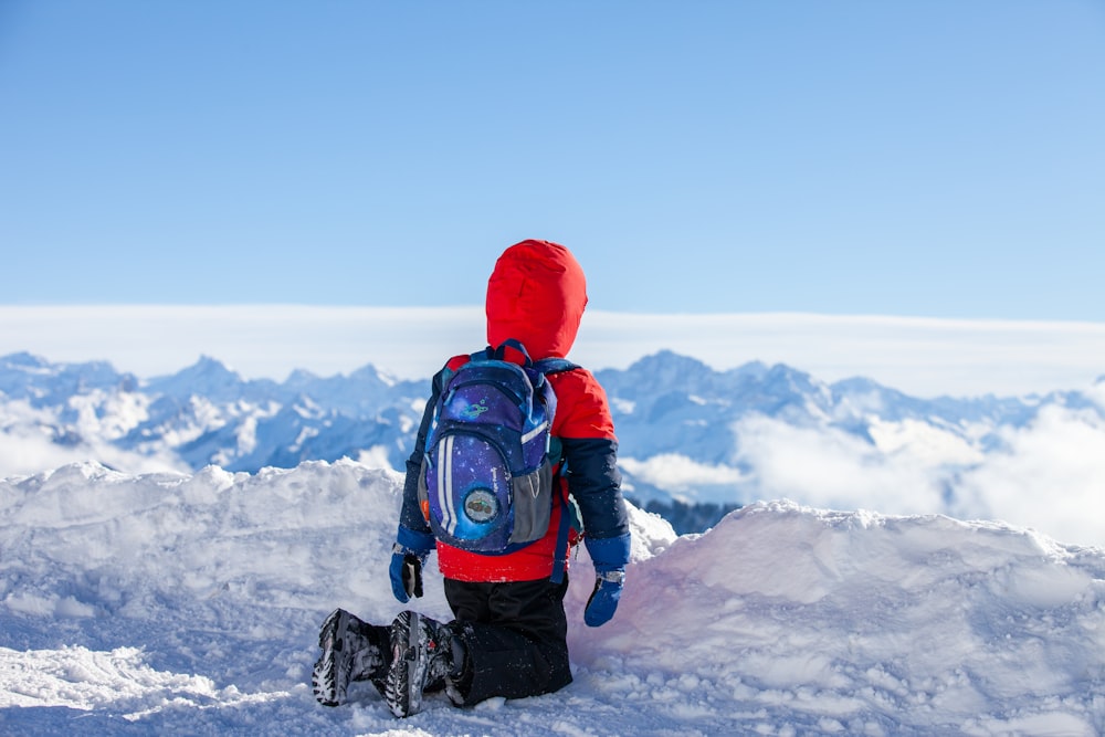 person in red knit cap and black jacket standing on snow covered ground during daytime