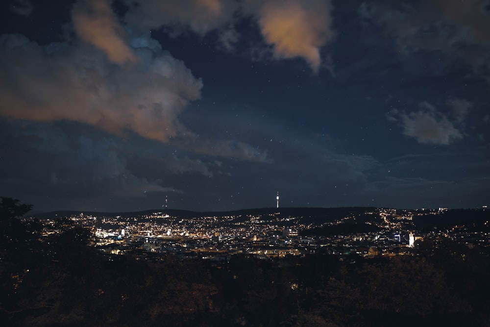 city skyline under cloudy sky during night time