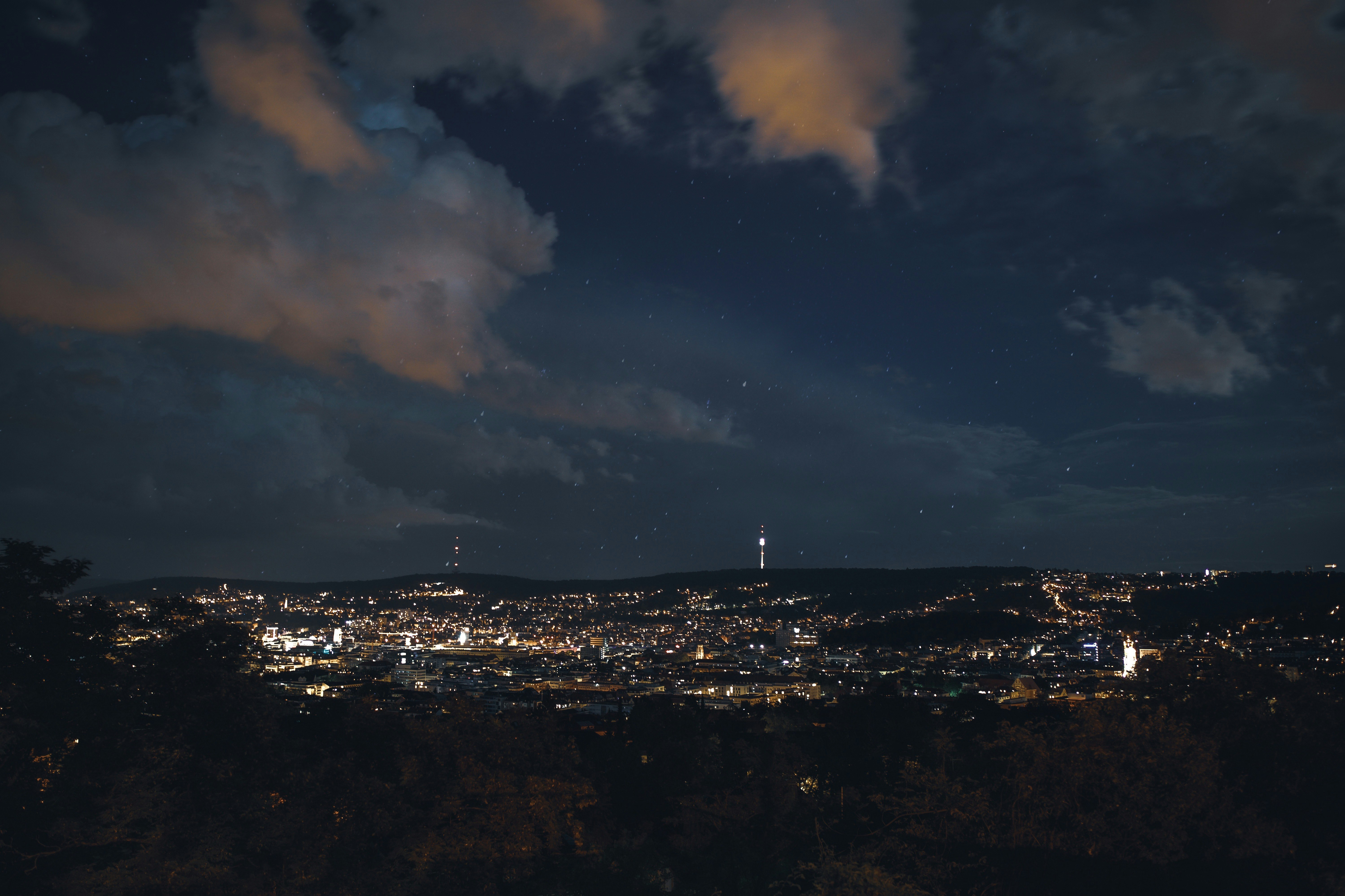 city skyline under cloudy sky during night time